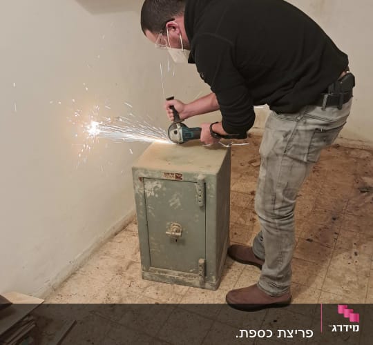 אדם חותך כספת עם כלי עבודה חשמלי